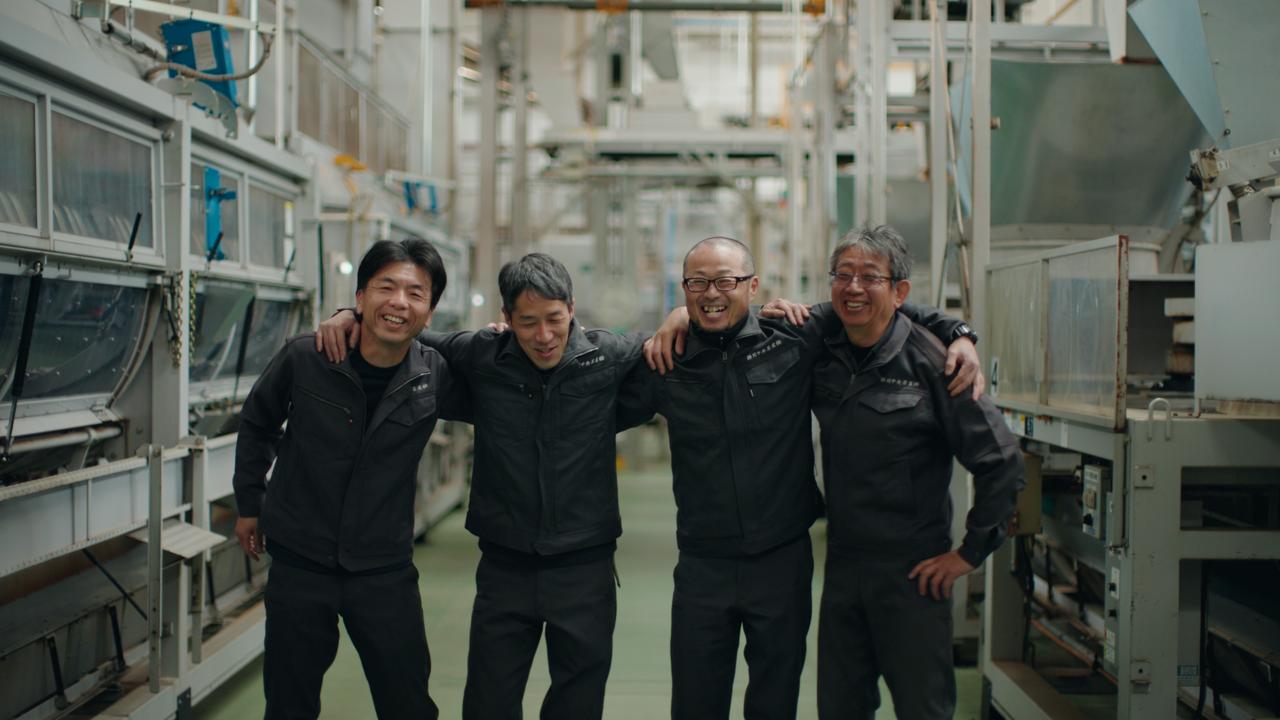 Four Sasaki Seicha production staff with arms around each other inside the tea refining factory in Kakegawa